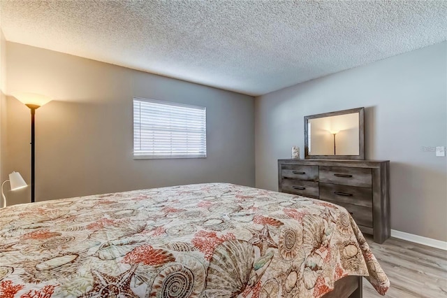 bedroom featuring a textured ceiling, wood finished floors, and baseboards