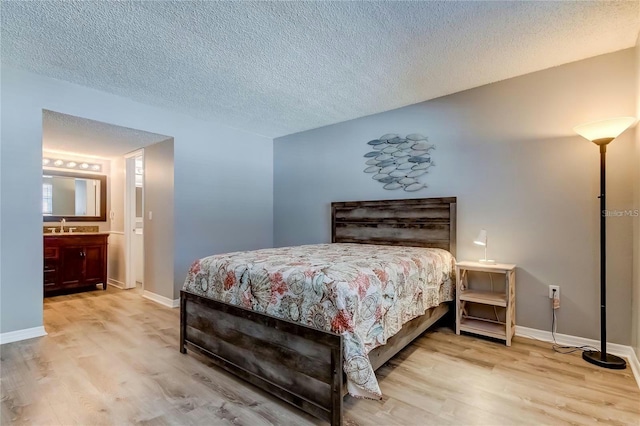 bedroom with a textured ceiling, a sink, wood finished floors, and baseboards