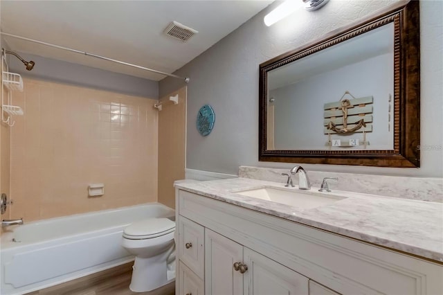 bathroom featuring visible vents, bathing tub / shower combination, toilet, wood finished floors, and vanity