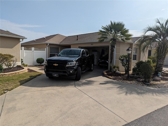 view of side of property featuring stucco siding, driveway, a garage, and fence