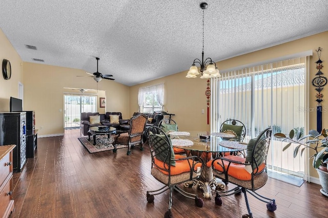 dining space with vaulted ceiling, dark wood-style floors, visible vents, and a textured ceiling