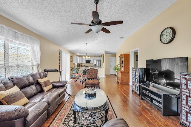 living room with ceiling fan, lofted ceiling, a textured ceiling, and wood finished floors