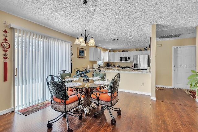 dining space featuring baseboards, a textured ceiling, a healthy amount of sunlight, and wood finished floors