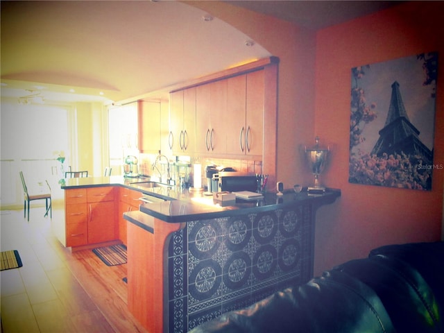 kitchen featuring a peninsula, stainless steel microwave, a sink, and light wood-style floors