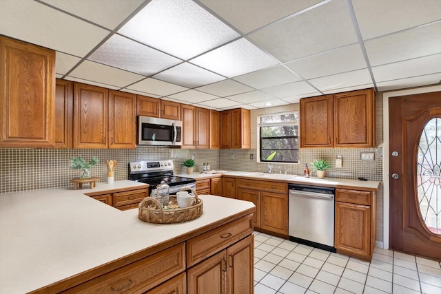 kitchen featuring tasteful backsplash, brown cabinets, stainless steel appliances, and light countertops