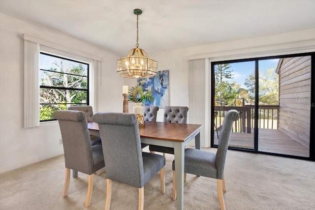 dining room featuring a notable chandelier, light colored carpet, and baseboards