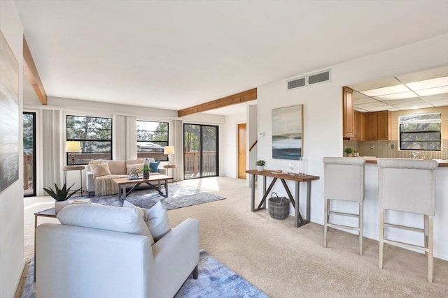 living room with beam ceiling, light colored carpet, and a paneled ceiling