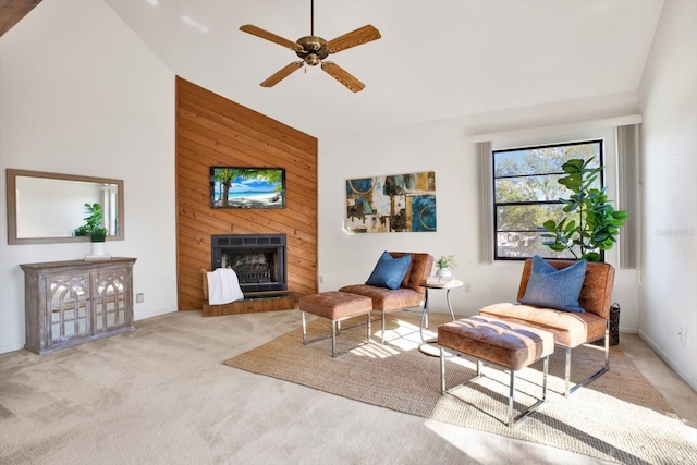 living area with a large fireplace, ceiling fan, and carpet floors