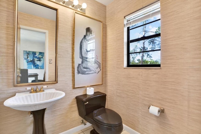 half bathroom with tile patterned floors, toilet, and a sink