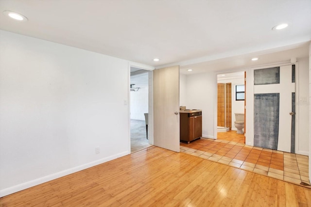 unfurnished room featuring light wood finished floors, recessed lighting, and baseboards