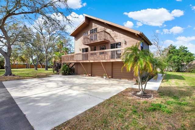 rear view of property featuring a balcony, a lawn, a garage, and driveway