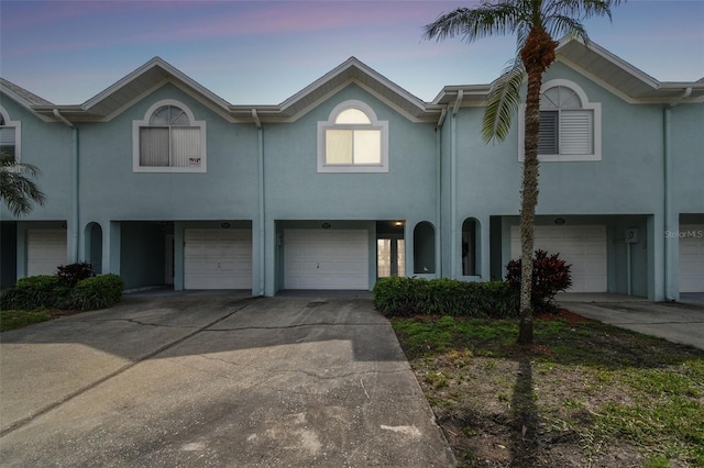 multi unit property featuring driveway, an attached garage, and stucco siding