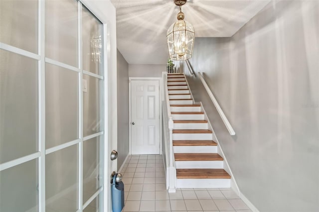 staircase featuring a chandelier, tile patterned flooring, and baseboards