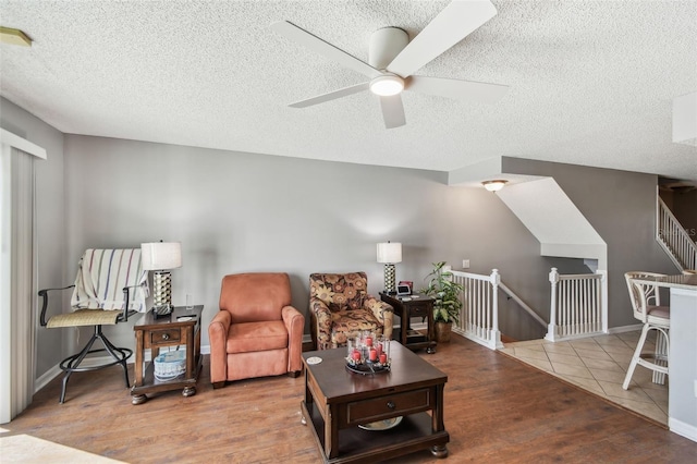 living room featuring a textured ceiling, baseboards, and wood finished floors