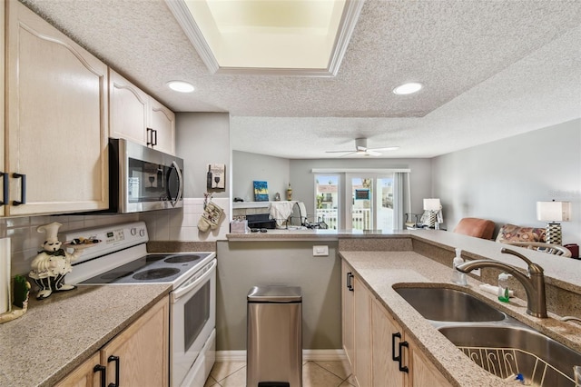 kitchen featuring electric range, stainless steel microwave, open floor plan, and a sink