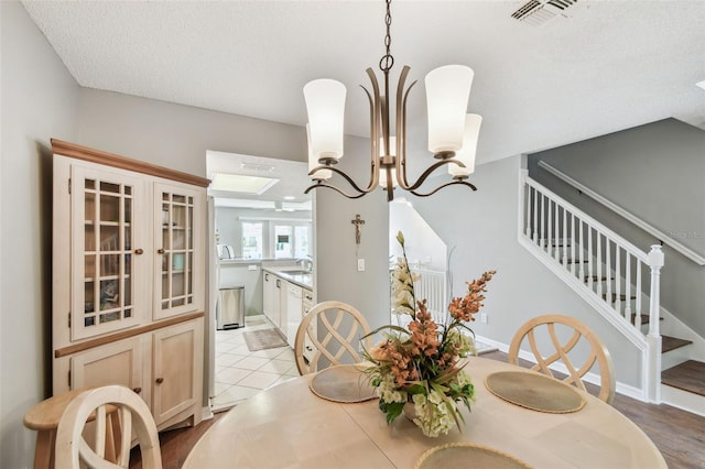 dining room featuring light tile patterned floors, a textured ceiling, visible vents, stairs, and an inviting chandelier