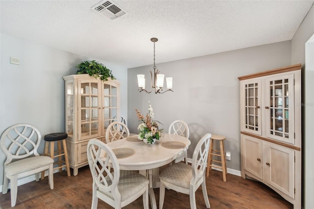 dining area featuring a chandelier, visible vents, dark wood finished floors, and a textured ceiling