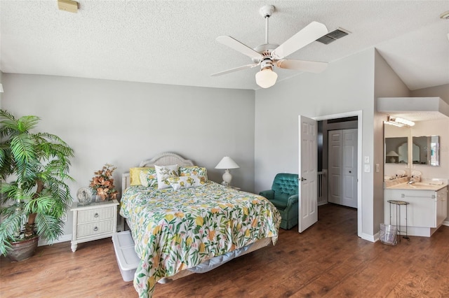 bedroom with a sink, visible vents, vaulted ceiling, and wood finished floors