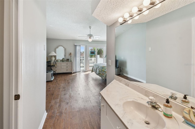 bathroom featuring connected bathroom, a ceiling fan, wood finished floors, a textured ceiling, and vanity