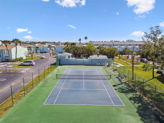 view of tennis court featuring fence and a residential view