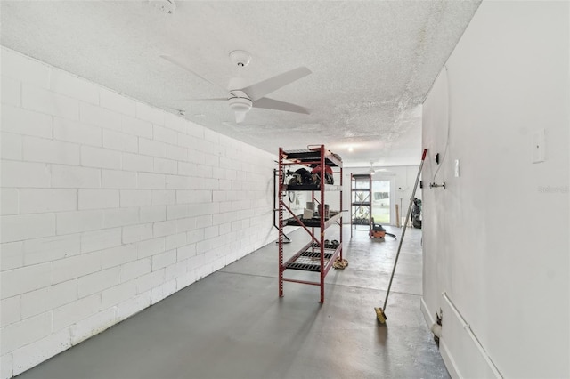 workout area with a textured ceiling, ceiling fan, and concrete block wall