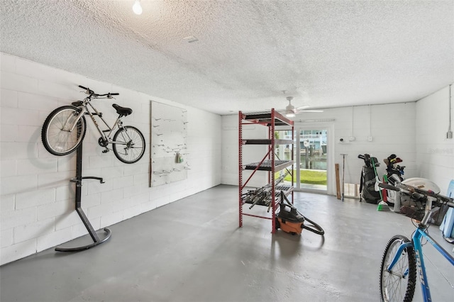 workout room with a ceiling fan, concrete block wall, and a textured ceiling