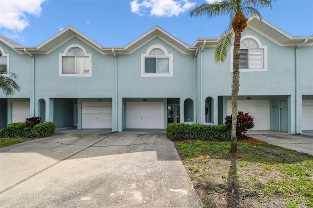 multi unit property with a garage, driveway, and stucco siding