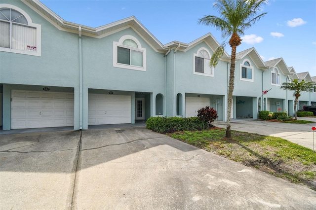 multi unit property with driveway, an attached garage, and stucco siding