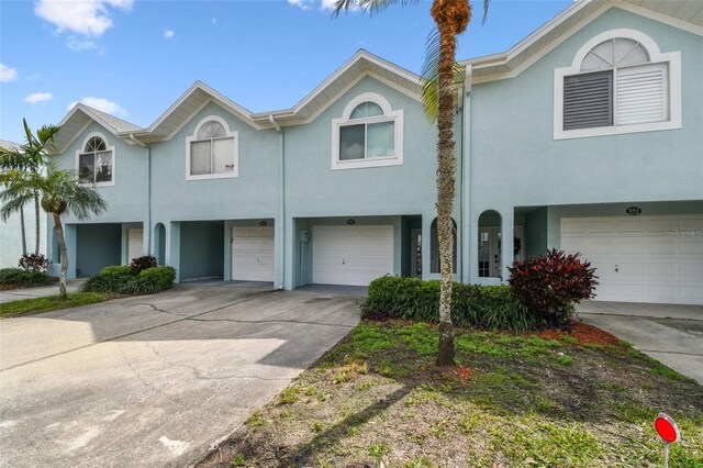 multi unit property with driveway, an attached garage, and stucco siding