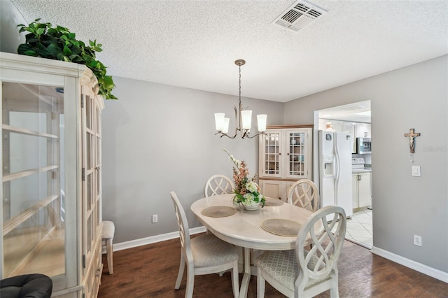 dining space featuring baseboards, a textured ceiling, visible vents, and wood finished floors