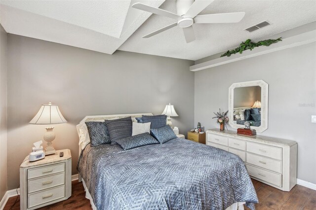 bedroom featuring baseboards, visible vents, a ceiling fan, dark wood-style floors, and a textured ceiling