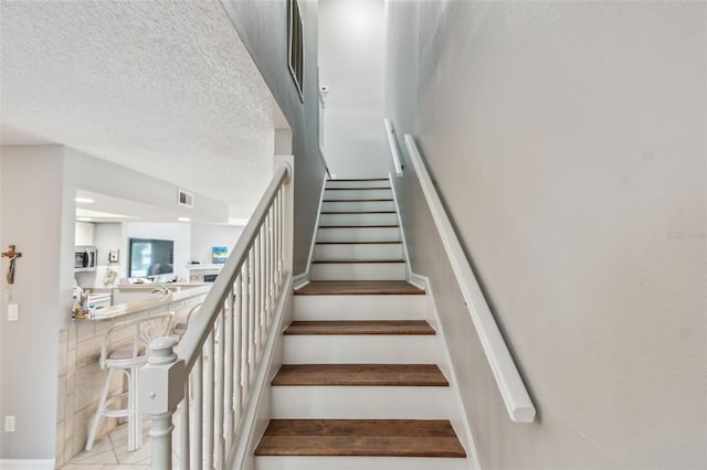 staircase featuring a textured ceiling