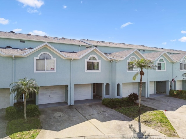 multi unit property with a garage, driveway, and stucco siding