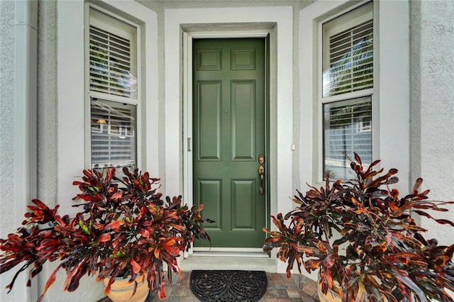 doorway to property with covered porch and stucco siding