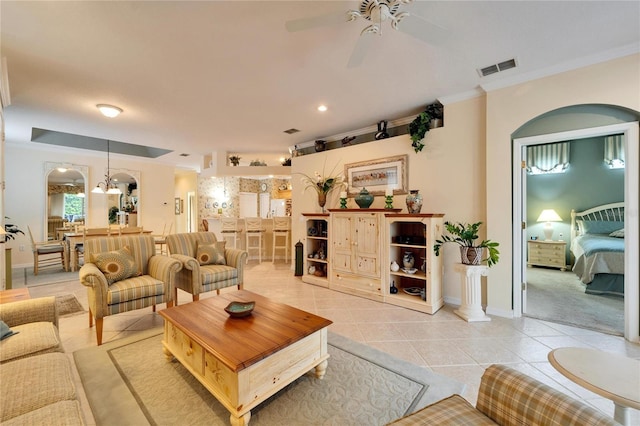 living area featuring light tile patterned floors, baseboards, visible vents, ceiling fan, and ornamental molding