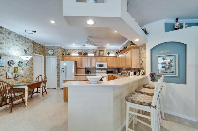 kitchen featuring a peninsula, white appliances, ornamental molding, and a sink