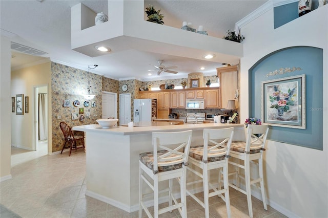 kitchen with a peninsula, white appliances, visible vents, ornamental molding, and wallpapered walls