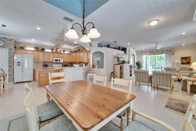 dining area with ornamental molding, arched walkways, visible vents, and ceiling fan with notable chandelier