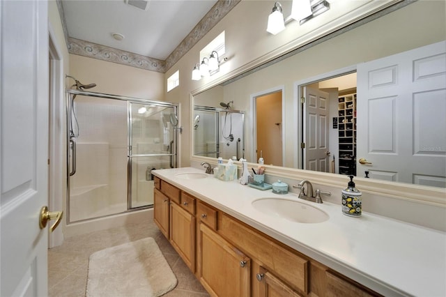 bathroom with double vanity, a stall shower, a sink, and tile patterned floors