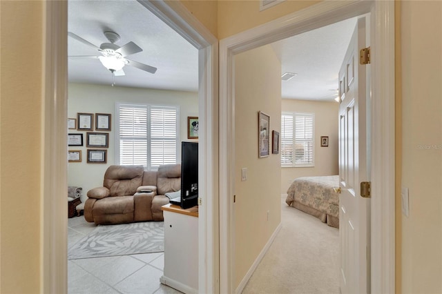 hall featuring light carpet, visible vents, and baseboards