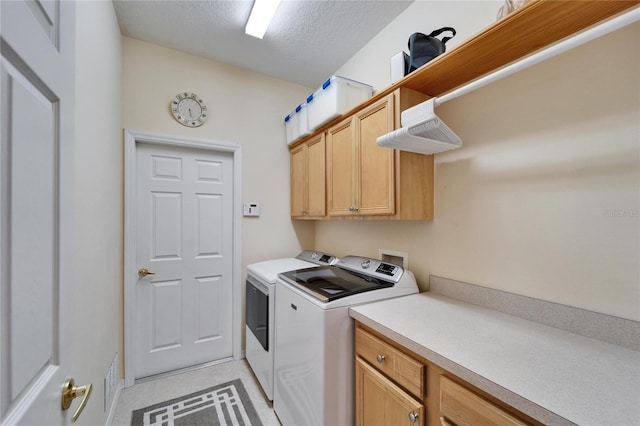 washroom featuring cabinet space, washer and clothes dryer, and a textured ceiling