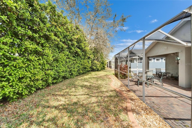 view of yard with glass enclosure and a patio