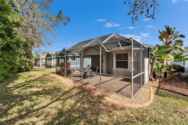 rear view of property with a lanai, a patio area, and a lawn