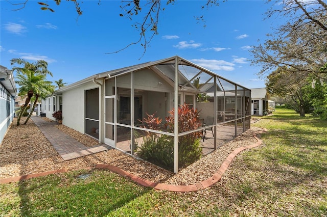 rear view of property with glass enclosure and a lawn