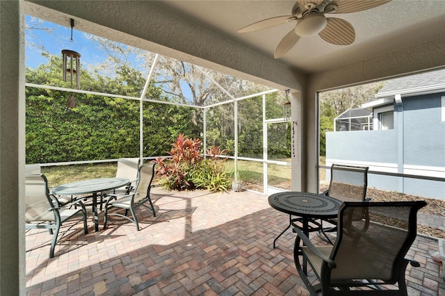 view of patio with outdoor dining area, a lanai, and a ceiling fan