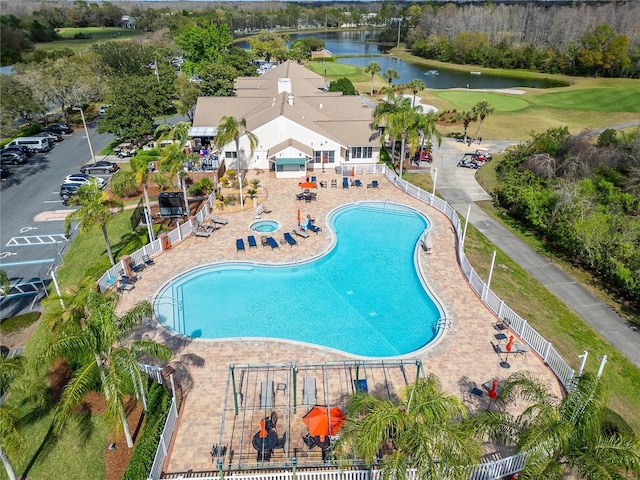 community pool with view of golf course, a water view, and fence