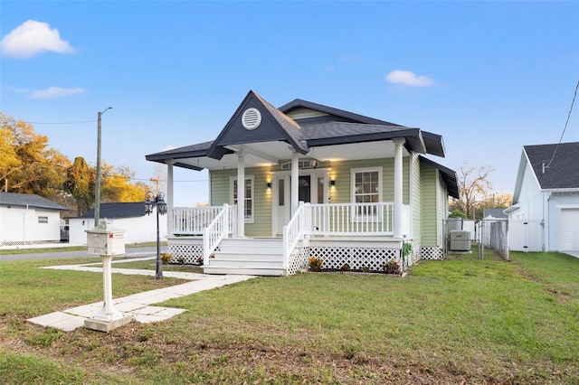 bungalow-style home with covered porch, a front yard, a gate, and central air condition unit