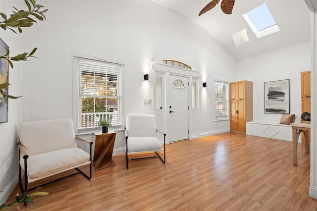 foyer entrance with a skylight, a healthy amount of sunlight, ceiling fan, and light wood-style flooring