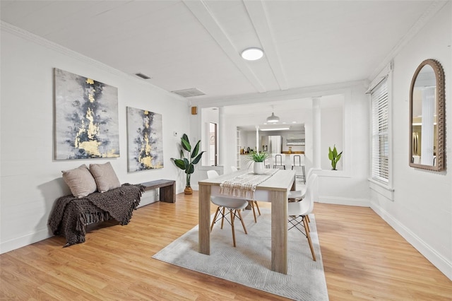 dining area featuring light wood finished floors, plenty of natural light, and crown molding