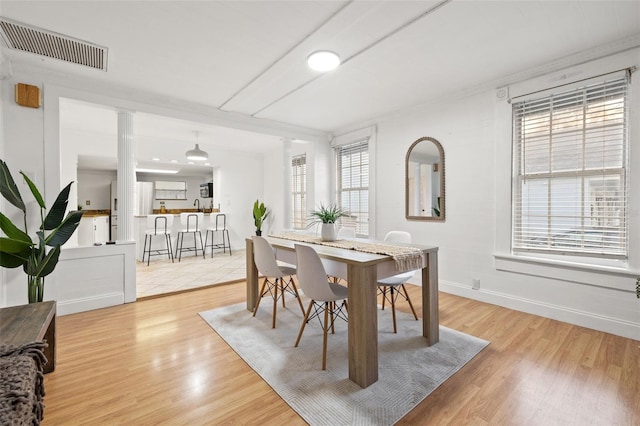 dining area with baseboards, decorative columns, visible vents, and light wood-style floors